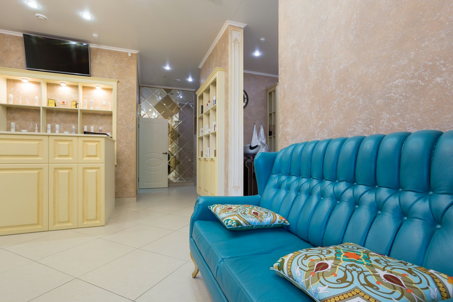 Turquoise tufted sofa with decorative pillows in a salon waiting area.