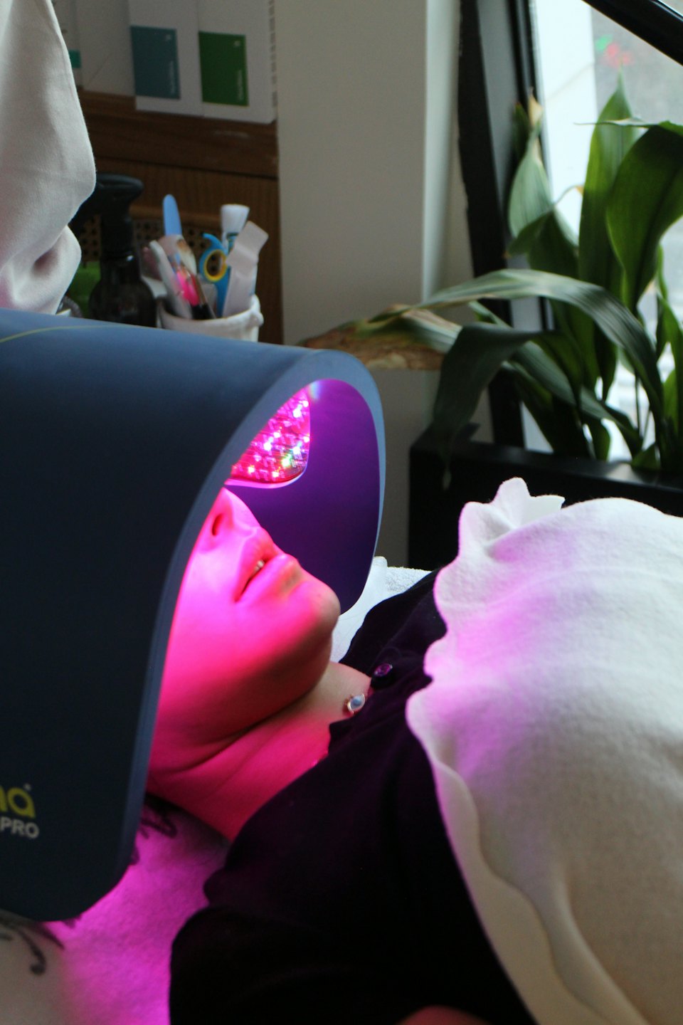 A person lies under a glowing LED light therapy device.