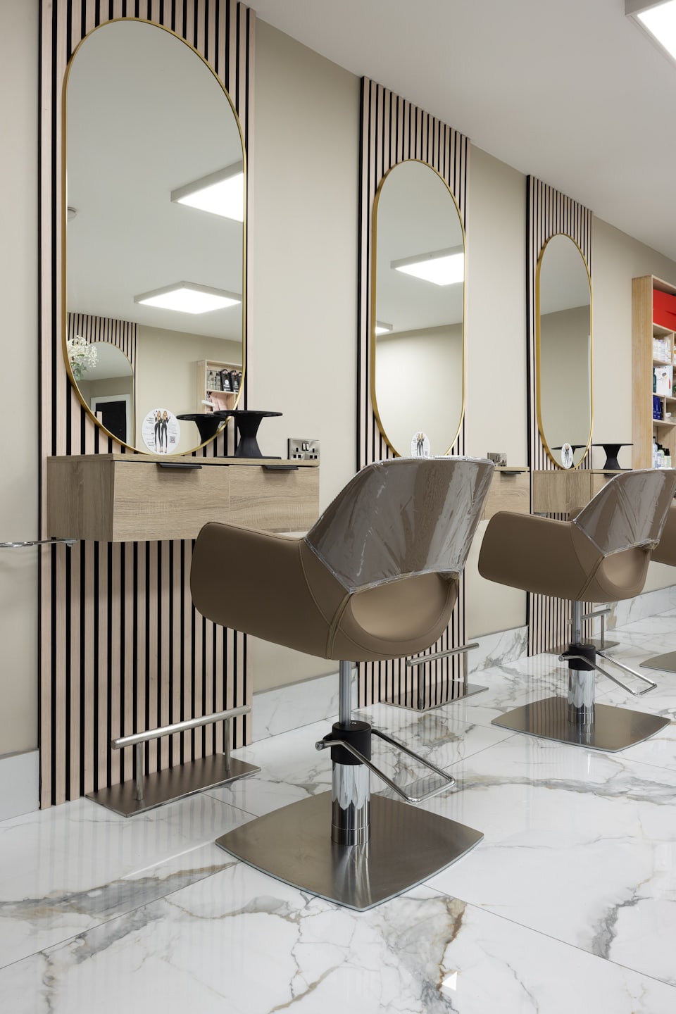 Unoccupied modern hair salon styling stations with gold accents.