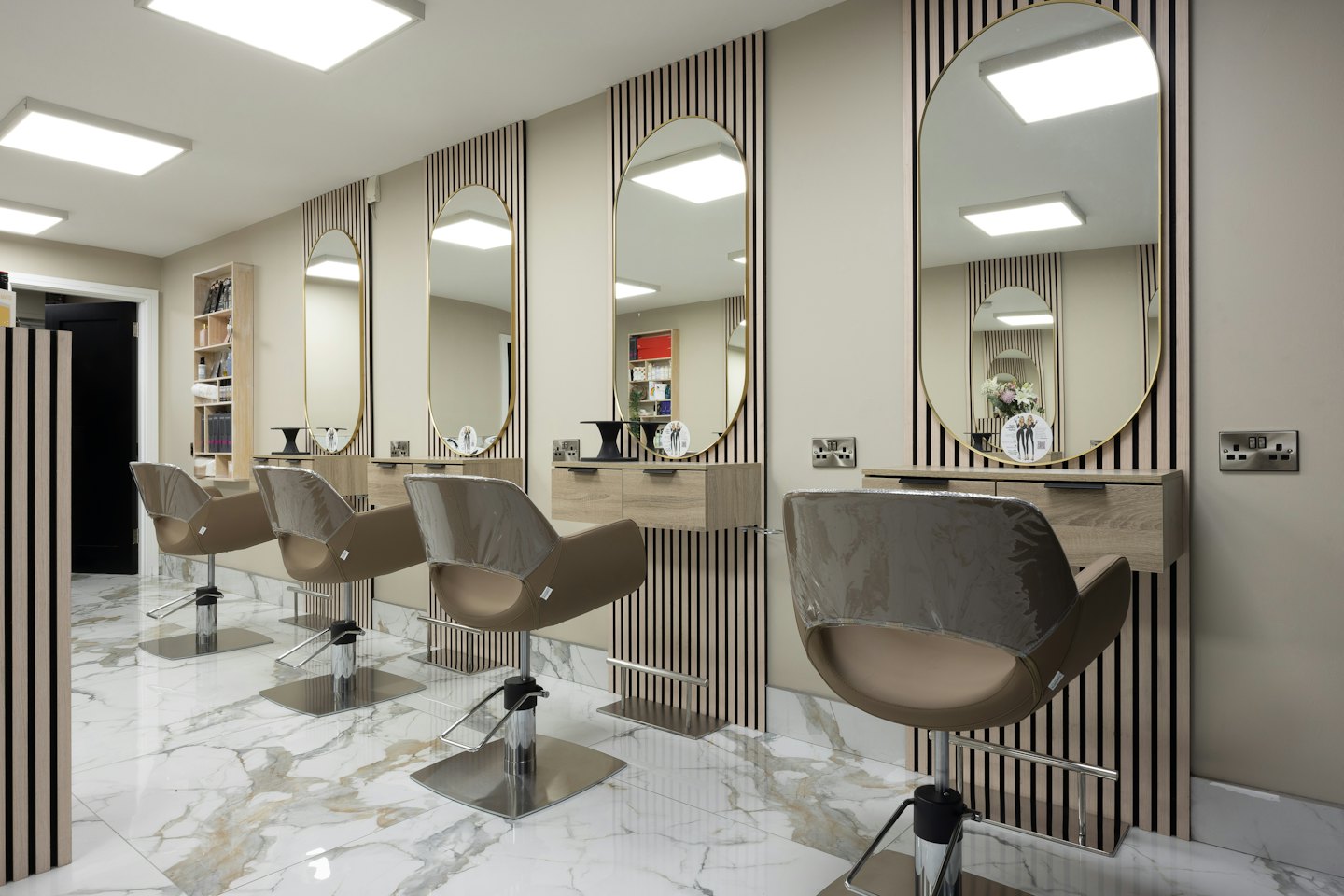Empty modern hair salon with styling stations and marble floors.