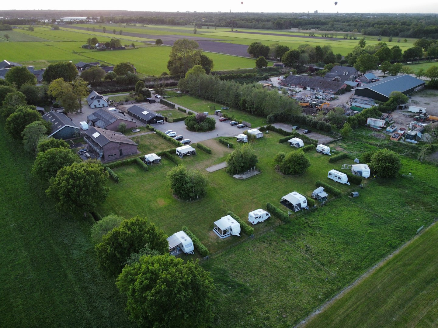 Recreational vehicles parked on grassy pitches in a rural landscape.