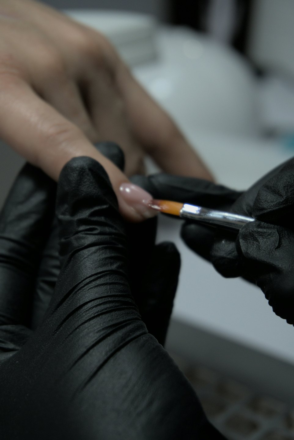 Nail technician using a brush to apply gel polish.
