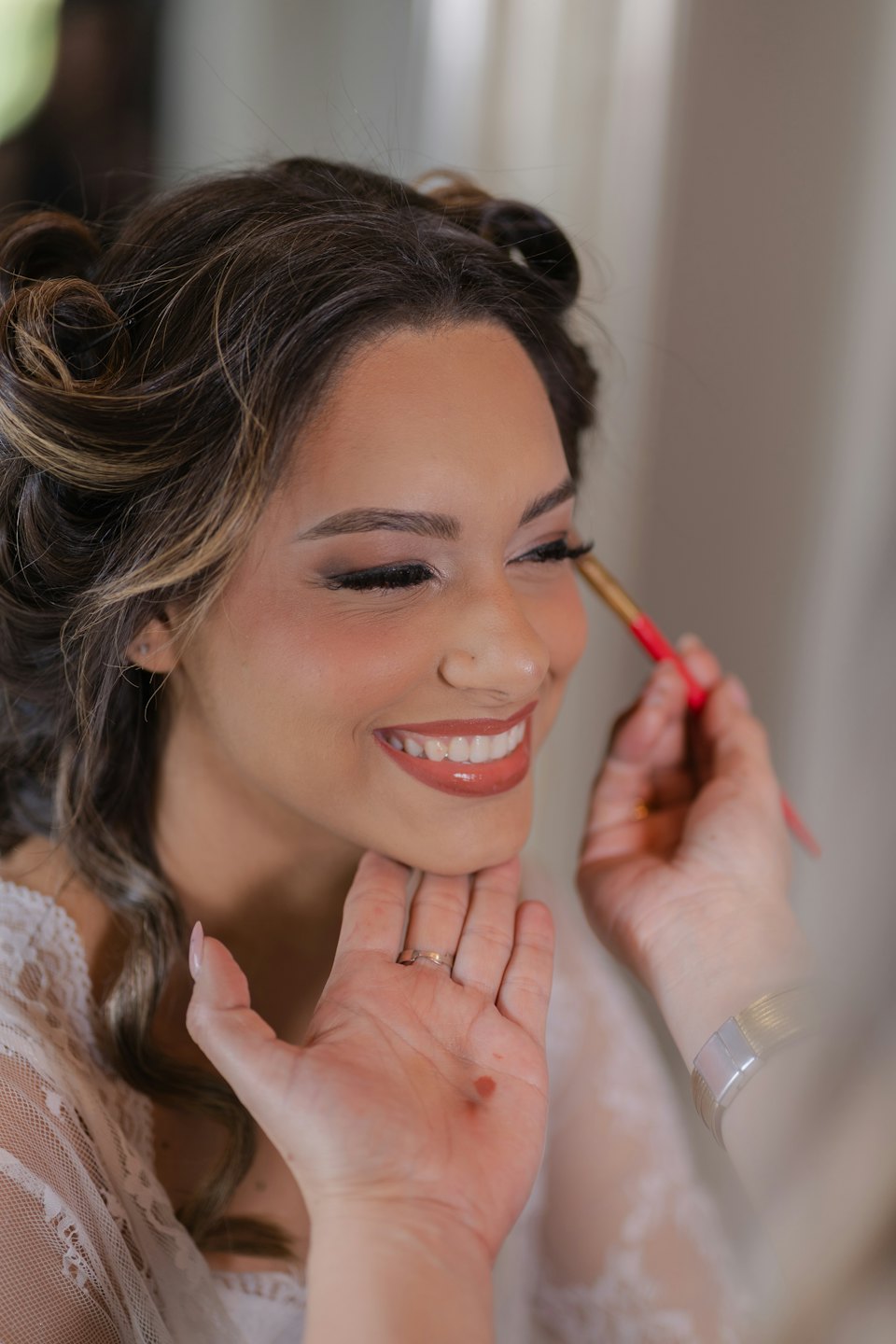 Makeup artist applies eyeshadow to a client in a robe.